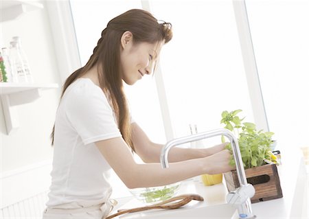 Woman picking herbs from planter Stock Photo - Premium Royalty-Free, Code: 669-03708187