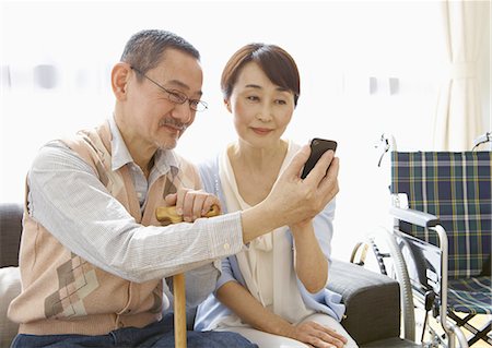 Senior couple using a smartphone on a sofa Stock Photo - Premium Royalty-Free, Code: 670-06025026