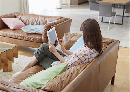 Middle-aged woman using a tablet PC on a sofa Stock Photo - Premium Royalty-Free, Code: 670-06025165