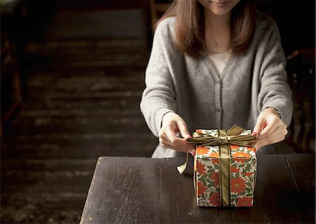 Woman tying a gift box with a ribbon Stock Photo - Premium Royalty-Free, Code: 670-06450741