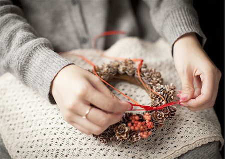 Woman tying a pinecone wreath with a ribbon Stock Photo - Premium Royalty-Free, Code: 670-06450753