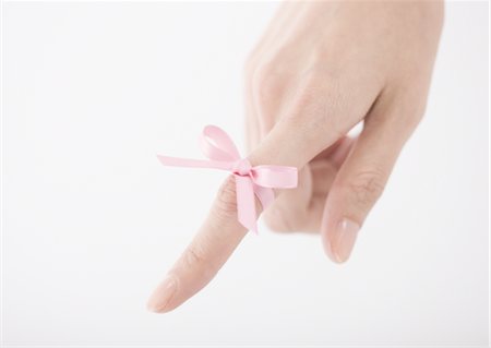 Pink ribbon tied on woman's finger Stock Photo - Premium Royalty-Free, Code: 670-03886936
