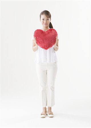 Woman holding heart-shaped cushion Stock Photo - Premium Royalty-Free, Code: 670-03886971