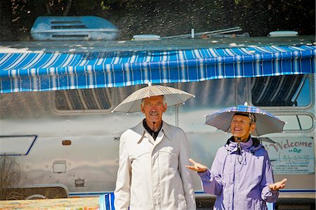 pouring rain on people - Senior couple in rain hats near airstream camper Stock Photo - Premium Royalty-Free, Code: 673-06025482