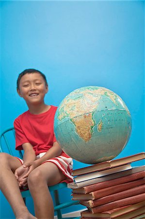 Boy seated near globe on top of books Foto de stock - Royalty Free Premium, Número: 673-06025510