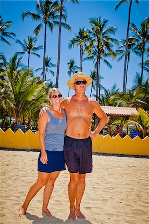 Man and woman arm in arm on beach near palm trees Foto de stock - Sin royalties Premium, Código: 673-06025664