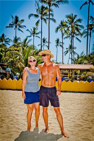 Man and woman arm in arm on beach near palm trees Stock Photo - Premium Royalty-Free, Code: 673-06025665