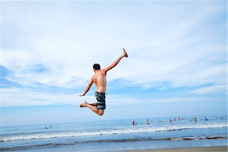 people jumping into water back view - Man leaping in air on beach Foto de stock - Sin royalties Premium, Código: 673-06964490