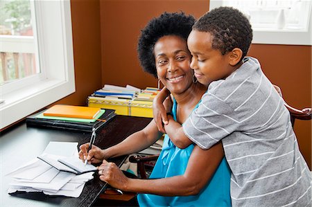 person writing in check book - Woman working at home office with son Stock Photo - Premium Royalty-Free, Code: 673-06964549