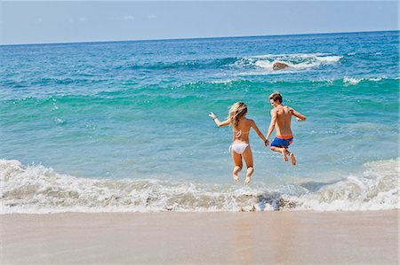 simsearch:6128-08748003,k - Young man and woman jumping in surf Stock Photo - Premium Royalty-Free, Code: 673-06964652