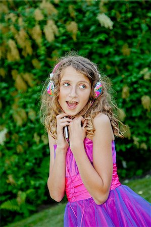 Teen girl in party dress listening to music outdoors Photographie de stock - Premium Libres de Droits, Code: 673-06964681
