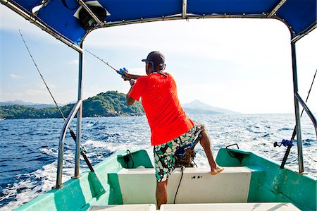 fishing pole in ocean pictures - Man fishing on charter boat Stock Photo - Premium Royalty-Free, Code: 673-06964751