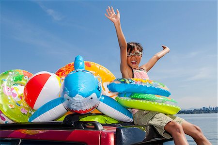 swim shark - Child poses beach toys and floaties on the roof of a car Stock Photo - Premium Royalty-Free, Code: 673-08139164