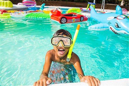 Boy wearing a scuba mask and snorkel swims in a pool full of inflatable toys Photographie de stock - Premium Libres de Droits, Code: 673-08139183