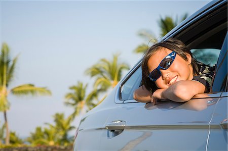 Boy in sunglasses leans out a car window against a tropical background Stock Photo - Premium Royalty-Free, Code: 673-08139213