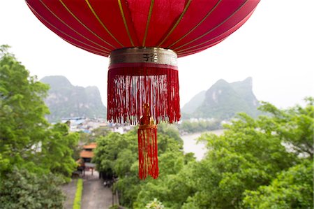 Red lantern hanging in front of a view of the Karst mountains and Li River, Yangshuo, China Stock Photo - Premium Royalty-Free, Code: 673-08139291