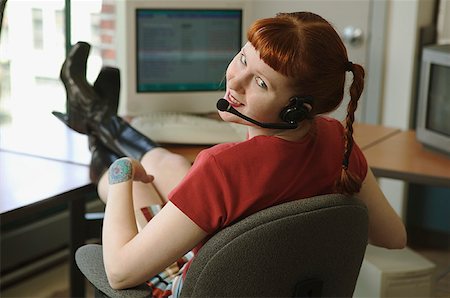 red pigtails - Red-headed woman talking on a headset phone with feet on desk. Stock Photo - Premium Royalty-Free, Code: 673-02137564