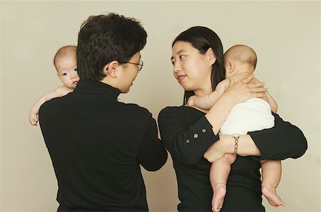 father with baby posing - Parents holding their twin babies. Stock Photo - Premium Royalty-Free, Code: 673-02137606