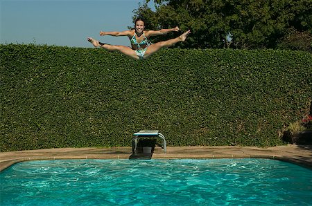 swimming pool candid - Teenage girl does the splits while jumping into a swimming pool. Stock Photo - Premium Royalty-Free, Code: 673-02137745