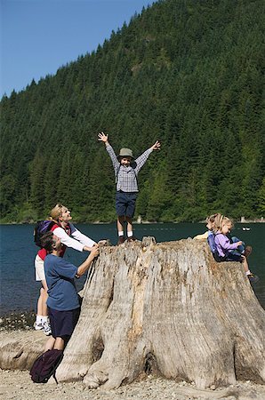 Family hikers playing around a big tree stump. Stock Photo - Premium Royalty-Free, Code: 673-02137819