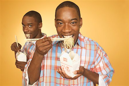 simsearch:673-02137877,k - Twin teen boys eating noodles from cartons. Foto de stock - Royalty Free Premium, Número: 673-02137884