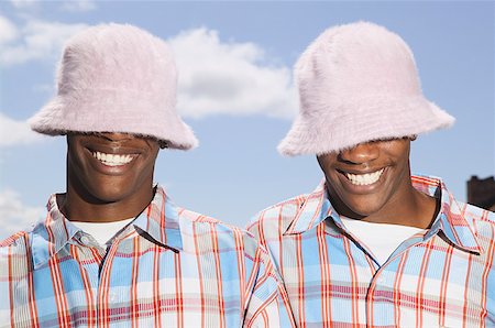 simsearch:673-02137877,k - Twin teenage boys in matching hats and shirts. Foto de stock - Royalty Free Premium, Número: 673-02137887