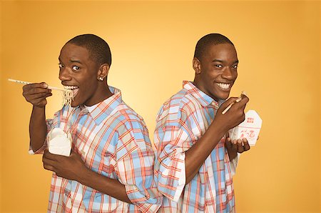Adolescent afro-américain jumeaux manger des nouilles de boîtes différentes. Photographie de stock - Premium Libres de Droits, Code: 673-02137883