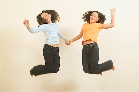simsearch:673-02137877,k - Twin teenage girls leaping in the air. Foto de stock - Royalty Free Premium, Número: 673-02137908