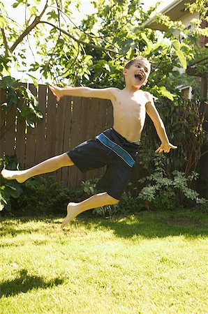 Young boy leaping in his backyard. Stock Photo - Premium Royalty-Free, Code: 673-02137957