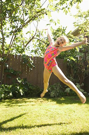 portrait of little girl swimsuit - Young girl in a swimming suit leaping in the air. Stock Photo - Premium Royalty-Free, Code: 673-02137958