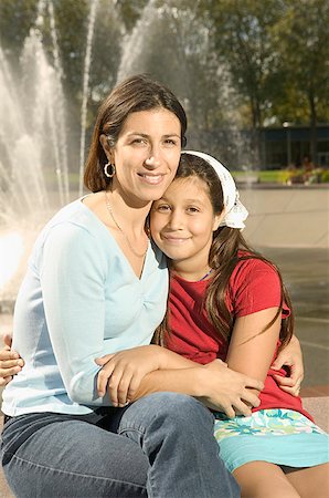 Mother hugging her daughter next to a fountain. Stock Photo - Premium Royalty-Free, Code: 673-02138048