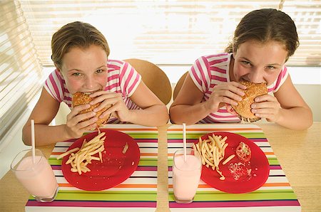 french fry smile - Twin teenage girls eating hamburgers. Stock Photo - Premium Royalty-Free, Code: 673-02138152