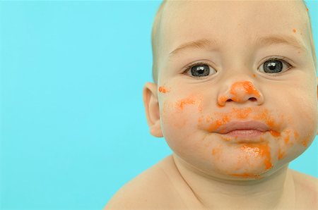 A baby with his face smeared with baby food. Stock Photo - Premium Royalty-Free, Code: 673-02138310