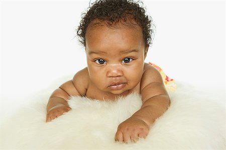 Baby girl crawling on a white fur rug. Stock Photo - Premium Royalty-Free, Code: 673-02138331
