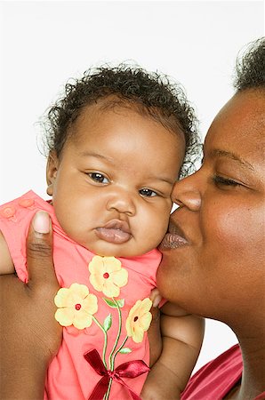 A mother kissing her baby girl on the cheek. Stock Photo - Premium Royalty-Free, Code: 673-02138333