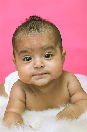 A baby girl lounging on a white rug. Stock Photo - Premium Royalty-Free, Code: 673-02138351