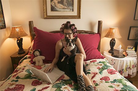 Woman in bed with her dog while working on personal finances. Stock Photo - Premium Royalty-Free, Code: 673-02138592