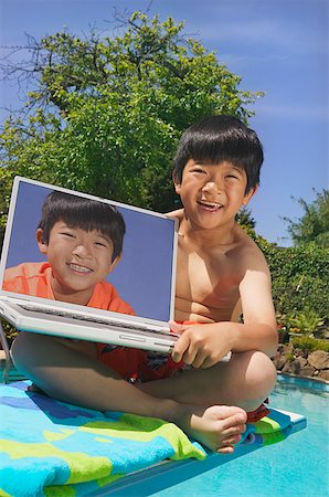 Une piscine de jeune garçon avec un ordinateur portable Photographie de stock - Premium Libres de Droits, Code: 673-02138706