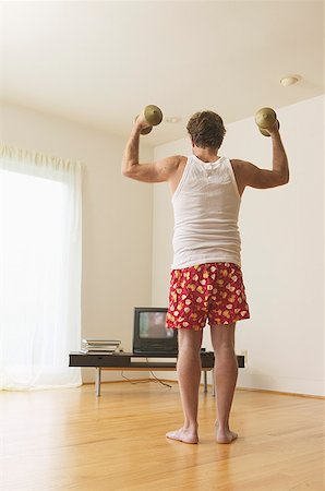 A middle-aged man lifting weights while watching TV Foto de stock - Royalty Free Premium, Número: 673-02138826