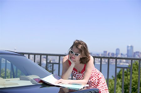 Woman leaning on car reading map Stock Photo - Premium Royalty-Free, Code: 673-02139391