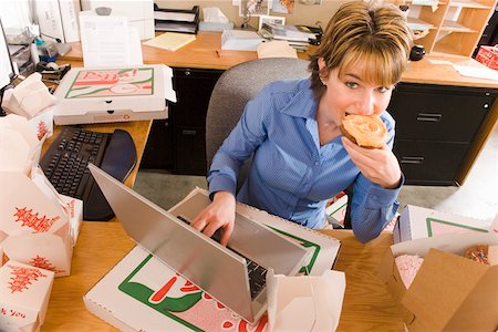 pigging out - Office worker eating at her desk Stock Photo - Premium Royalty-Free, Code: 673-02139664