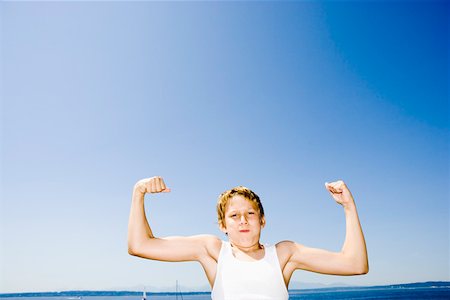 flexing muscles at beach - Young boy flexing his muscles Stock Photo - Premium Royalty-Free, Code: 673-02139789