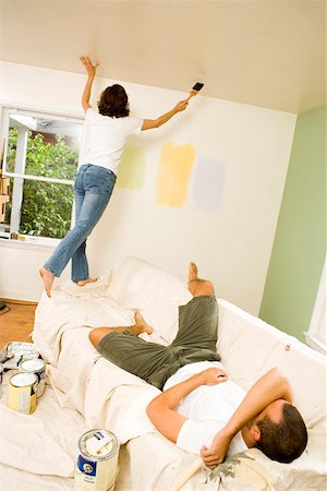 Woman painting walls while man rests Stock Photo - Premium Royalty-Free, Code: 673-02139866