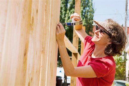 Smiling woman building fence Stock Photo - Premium Royalty-Free, Code: 673-02139926