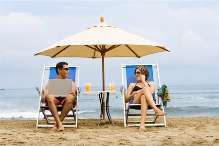 Couple using laptop and phone on beach Stock Photo - Premium Royalty-Free, Code: 673-02140071