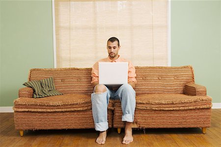 spartanisch - Mann sitzt auf der Couch mit laptop Stockbilder - Premium RF Lizenzfrei, Bildnummer: 673-02140087