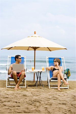 Couple using laptop and phone on beach Stock Photo - Premium Royalty-Free, Code: 673-02140098