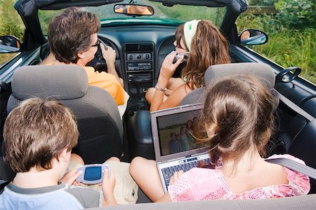 Family in convertible using portable electronics Stock Photo - Premium Royalty-Free, Code: 673-02140110