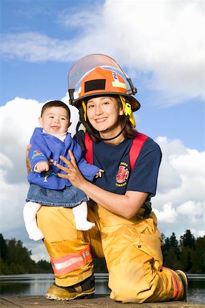 Portrait of female firefighter holding baby Stock Photo - Premium Royalty-Free, Code: 673-02140457