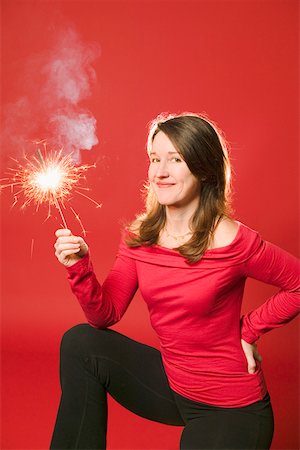 Smiling woman holding burning sparkler Foto de stock - Sin royalties Premium, Código: 673-02140570